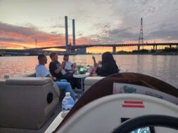 Friends celebrating a birthday party on a boat in Melbourne with city skyline in the background